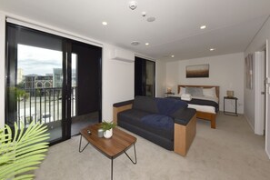 Ein modernes Hotelzimmer mit Balkon, einer Couch, einem Bett und einem kleinen Tisch.