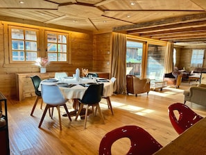 Ein Holzinnenraum mit Essbereich, Wohnzimmer und Blick ins Freie.