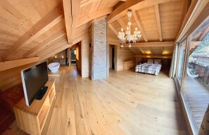 Ein geräumiges Schlafzimmer im Loftsstil mit einem großen Bett, einem Fernseher und einer Steinwand.