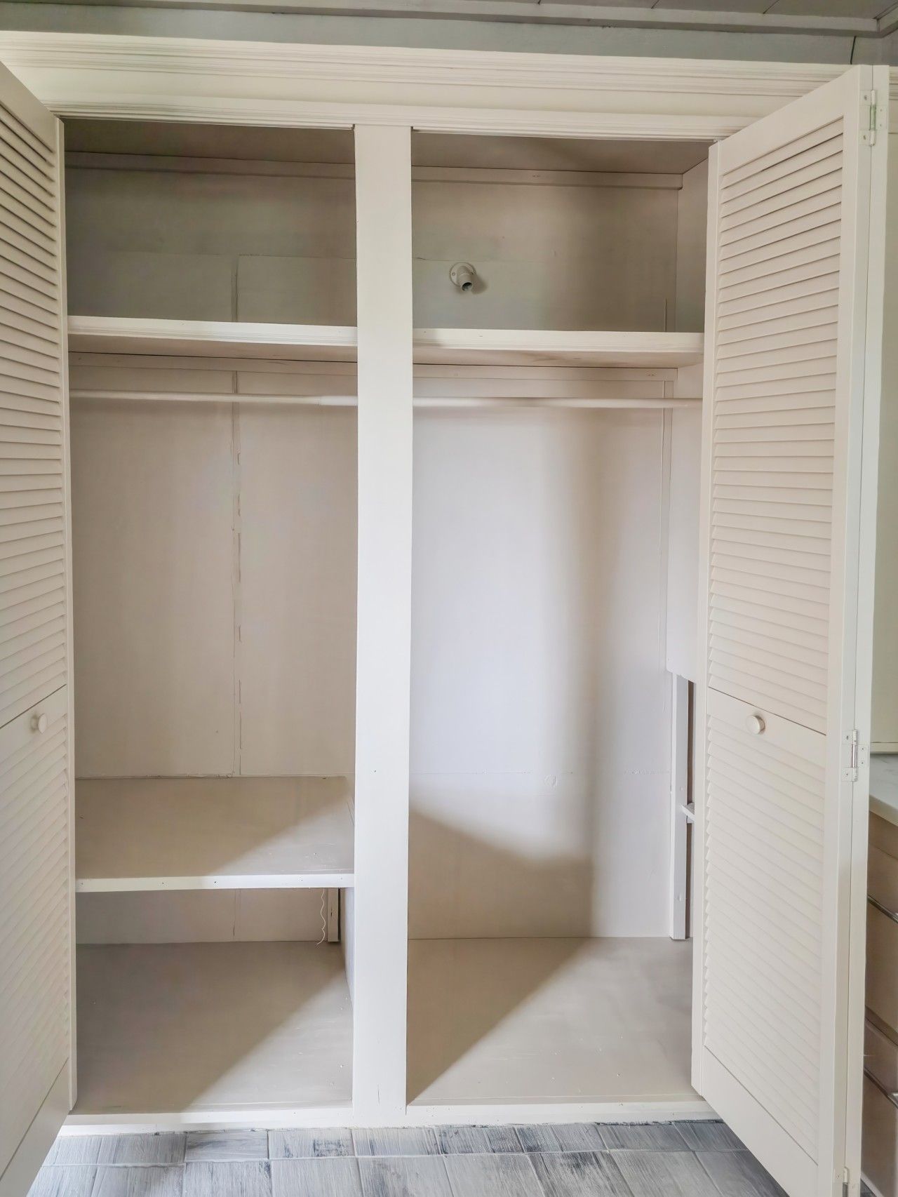 Un closet amplio y vacío, de color blanco, con puertas correderas y un solo estante.