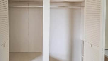 Un closet amplio y vacío, de color blanco, con puertas correderas y un solo estante.