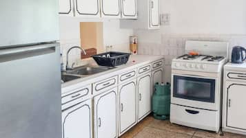 A kitchen with white cabinets, a stainless steel refrigerator, a gas stove, and a sink.