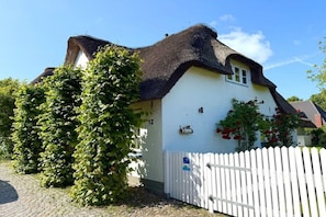 A traditional house with a thatched roof, a white exterior, and a white picket fence. - Holiday home in Wyk on Föhr with terrace (Wyk auf Föhr)