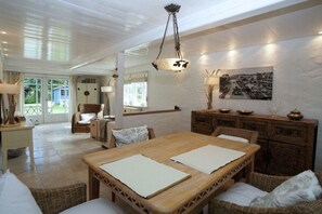 A spacious room with a wooden dining table, wicker furniture, and a view of the outdoors. - Holiday home in Wyk on Föhr with terrace (Wyk auf Föhr)