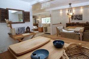 A dining area with a wooden table, chairs, and a hanging light fixture. - Holiday home in Wyk on Föhr with terrace (Wyk auf Föhr)