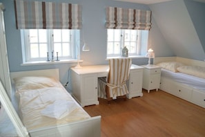 A bedroom with two beds, a desk, and a chair. There are windows with curtains, a lamp on the desk, and a nightstand with a lamp. - Holiday home in Dunsum with terrace (Dunsum)