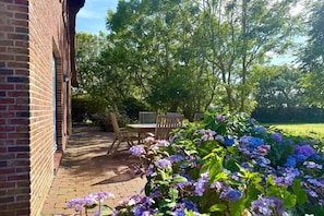 A brick building with a paved patio area, outdoor seating, and lush greenery. - Holiday home in Dunsum with terrace (Dunsum)