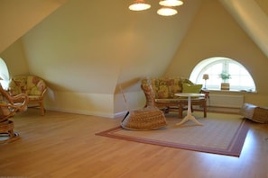 A room with a sloped ceiling, wicker furniture, a small table, and a window with a view. - Holiday home in Dunsum with terrace (Dunsum)