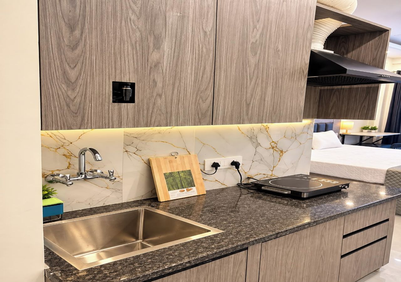 Una cocina con encimera de granito, pileta de acero inoxidable y placa de inducción negra.