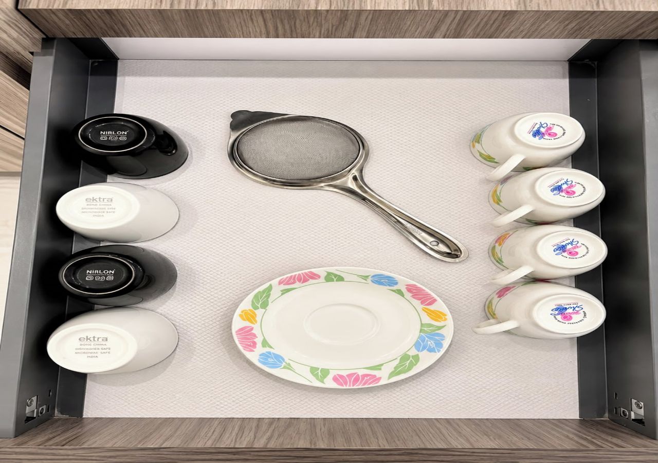 A drawer containing a strainer, two cups, and two containers.