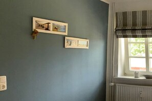 Una habitación con ventana, un radiador y dos cuadros en la pared.