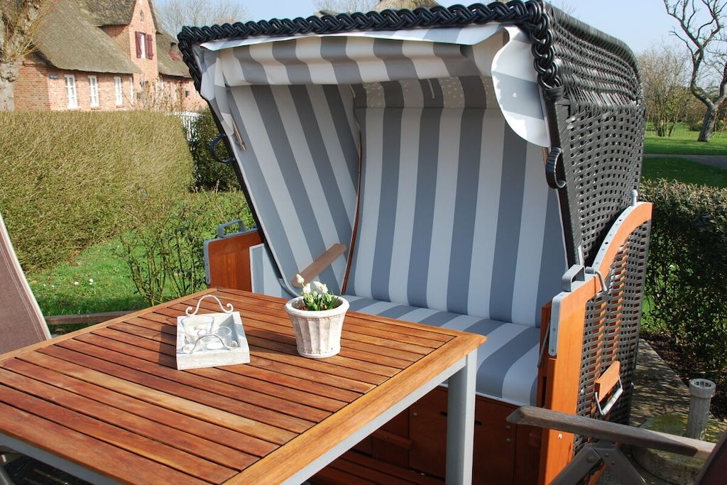 A wooden table with a striped cushion and a small potted plant.