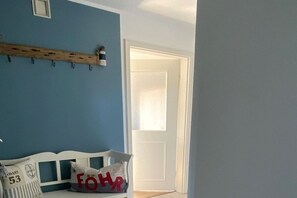 Una habitación con pared azul, un banco blanco y una puerta.