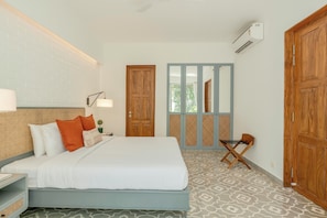 A hotel room with a bed, a nightstand, a lamp, a window with a view, and a wardrobe. - Staymaster Avyakta - 3BR Villa with Pool (Vagator)