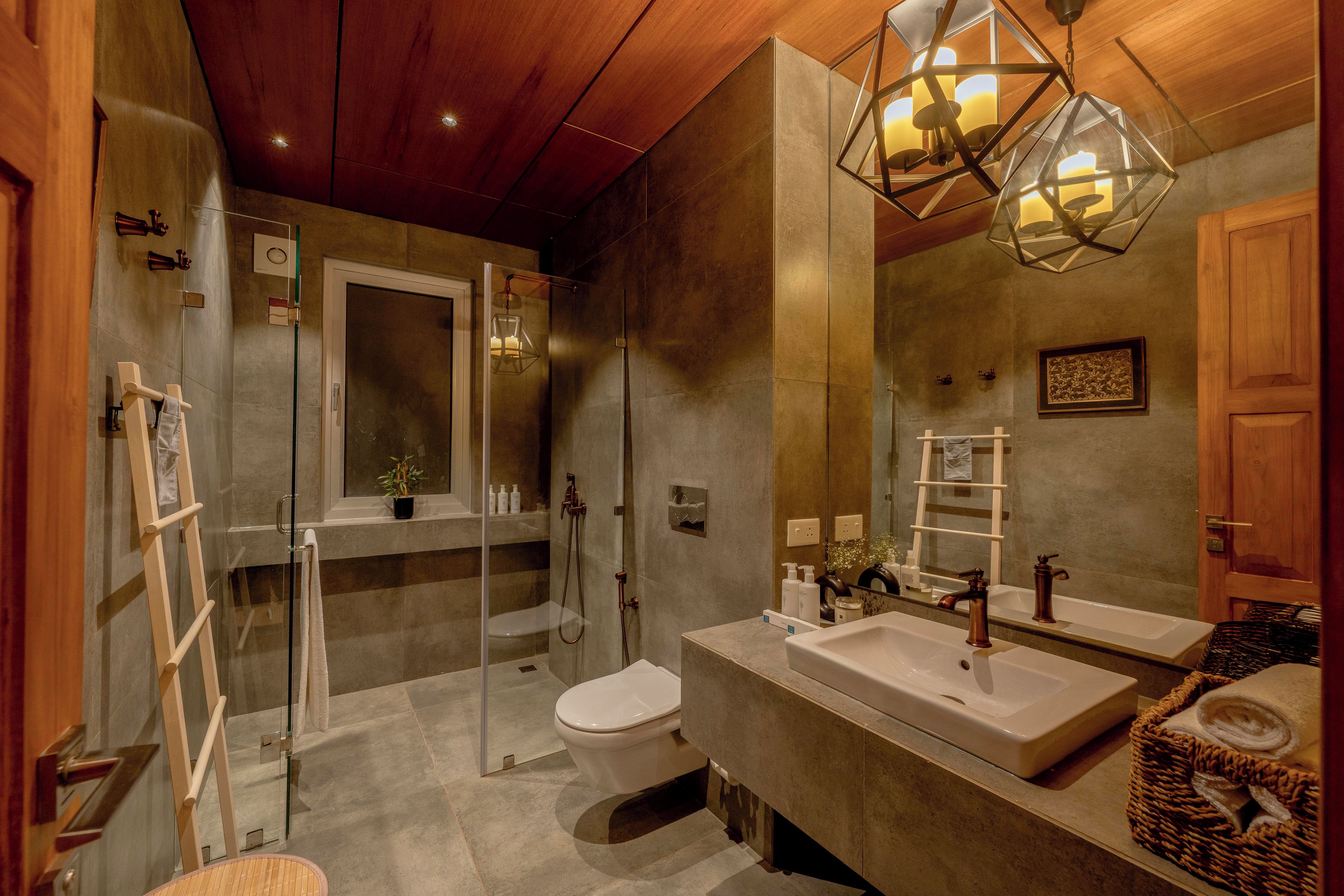 A modern bathroom with a glass shower enclosure, a toilet, a large vanity with dual sinks, and a wooden ceiling.