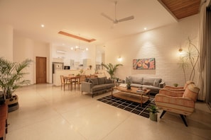 Una sala de estar moderna con sofá, sillones, una mesa de centro y un comedor con sillas y una mesa.