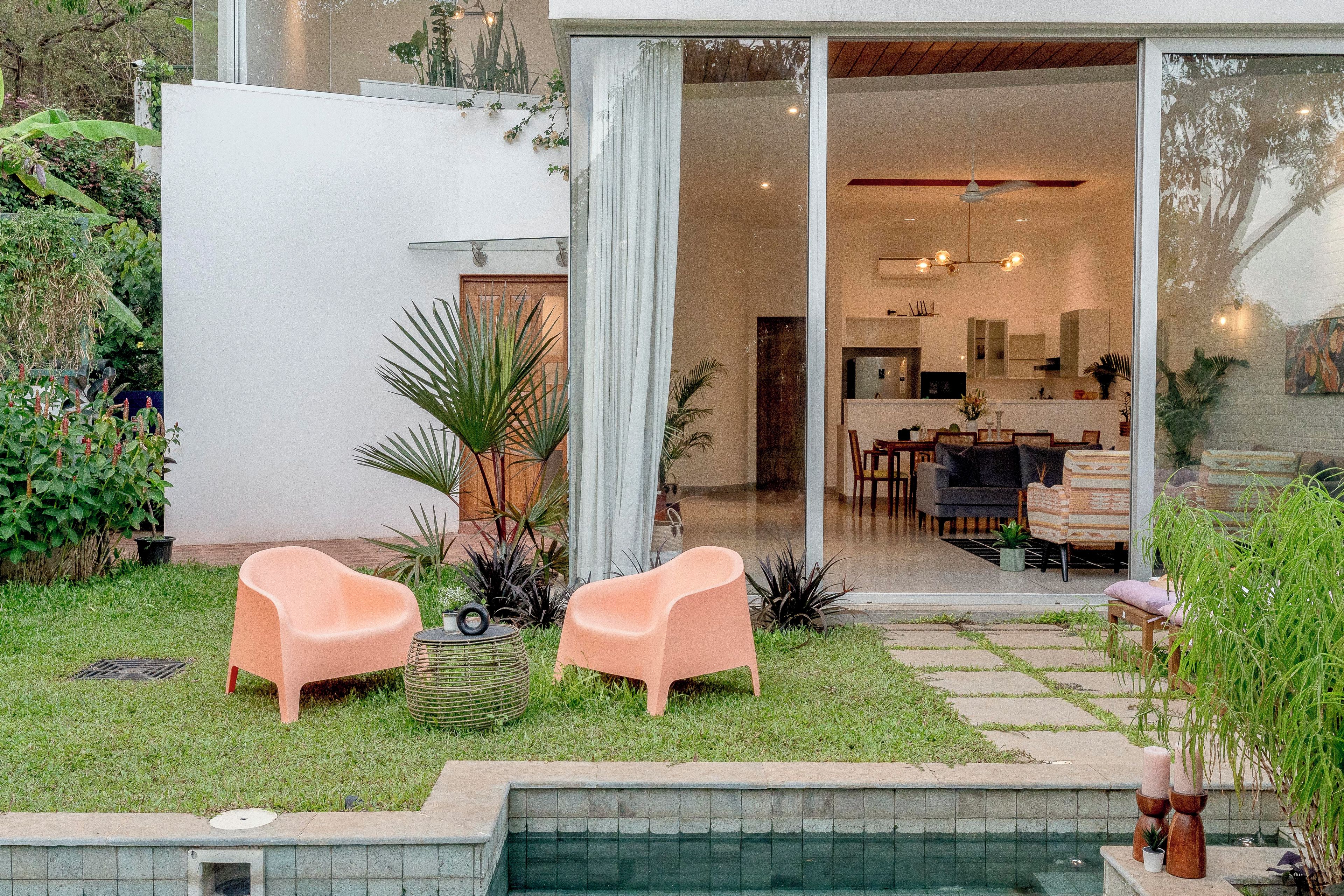 A modern outdoor patio with two chairs, a small table, and a pool.