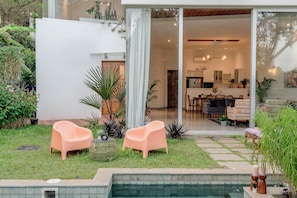 Un patio moderno al aire libre con dos sillas, una mesita y una piscina.