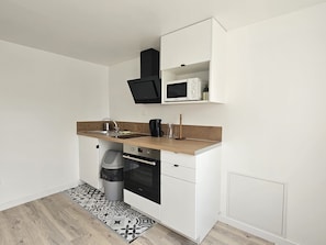 A compact kitchen with a microwave, oven, and sink. - New Listing (Thorigny-sur-Marne)