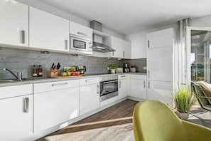 A modern kitchen with white cabinets, a stainless steel oven, and a microwave. - Holiday apartment with 2 bedrooms (Olpenitz)