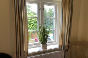 Ein Fenster mit einem Blumentopf, Vorhängen und einem Heizkörper darunter.