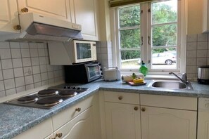 Eine Küche mit Herd, Mikrowelle, Toaster und einem Fenster mit Blick nach draußen.
