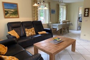 Ein Wohnzimmer mit einer schwarzen Ledersofa, einem Holztisch und einem Essbereich mit Tisch und Stühlen.