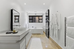 Ein modernes Badezimmer mit großem Spiegel, einer Badewanne, einer Dusche und einem Waschtisch.