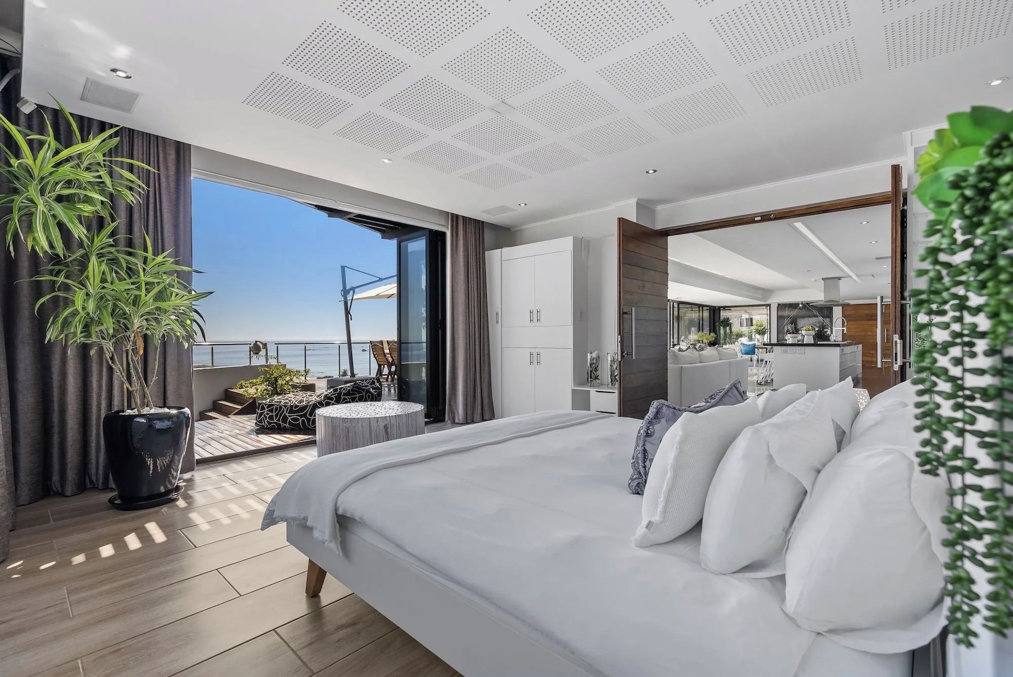 Ein modernes Schlafzimmer mit einem großen Bett, einem Balkon mit Blick und einer separaten Wohnbereiches.