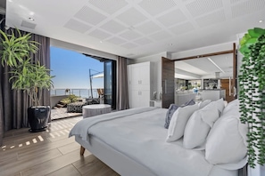 Ein modernes Schlafzimmer mit einem großen Bett, einem Balkon mit Blick und einer separaten Wohnbereiches.