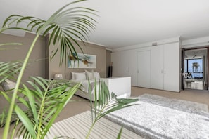 Quarto moderno com cama, guarda-roupa branco e vista para o mar através de uma porta.