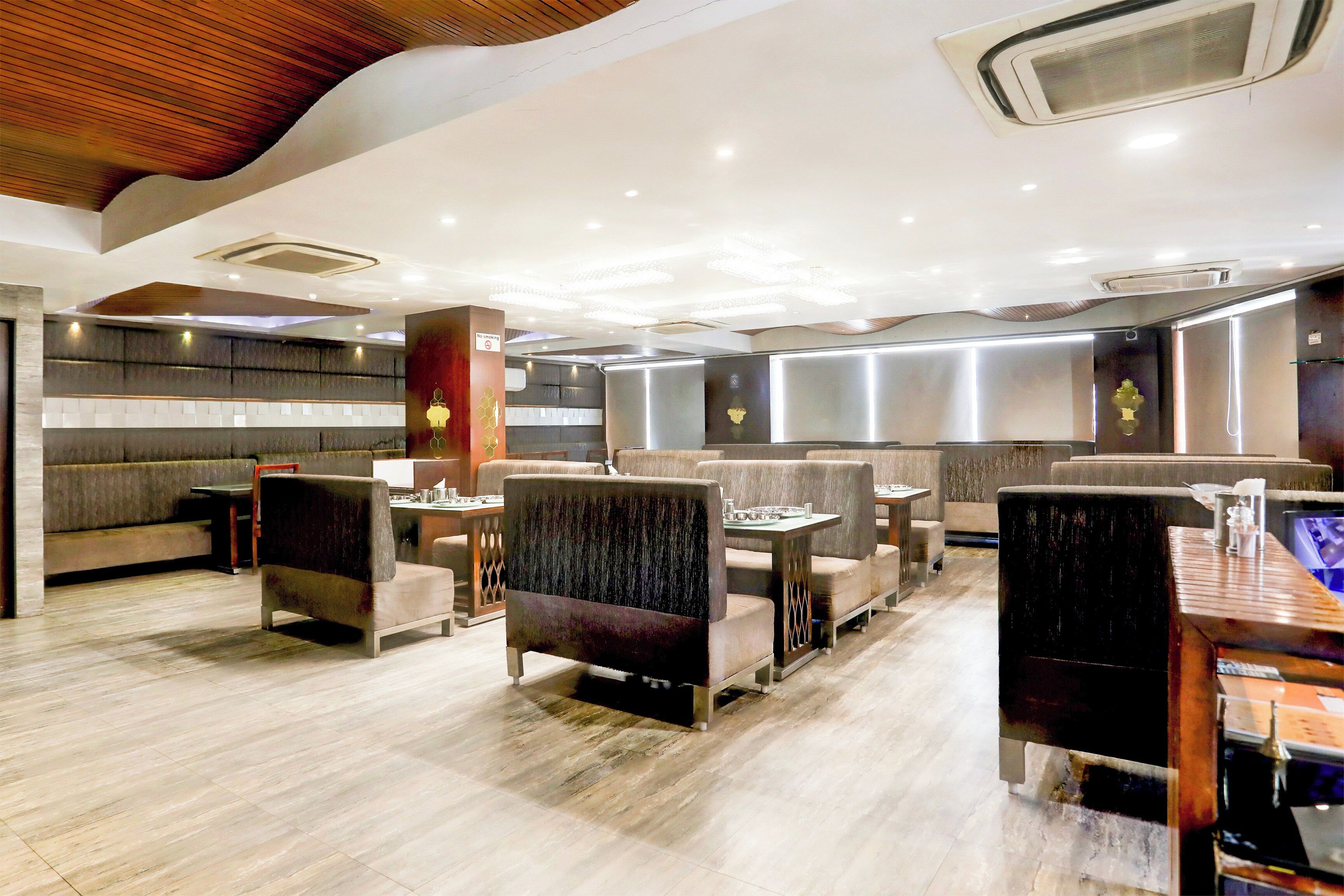 A modern restaurant interior with high ceilings, recessed lighting, and a variety of seating options including booths and tables.