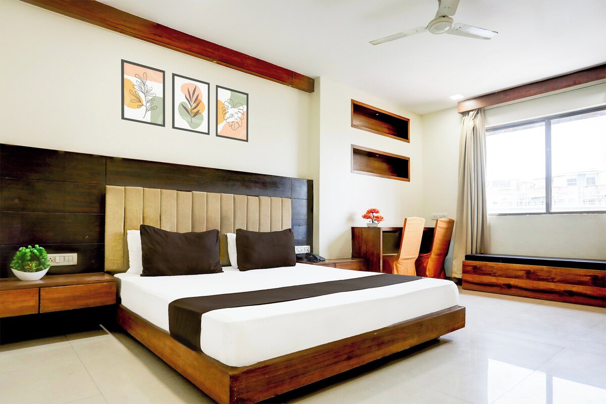 A modern hotel room with a large bed, a ceiling fan, and artwork on the wall.