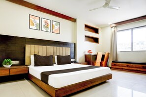 A modern hotel room with a large bed, a ceiling fan, and artwork on the wall. - Townhouse Prahladnagar (Ahmedabad)