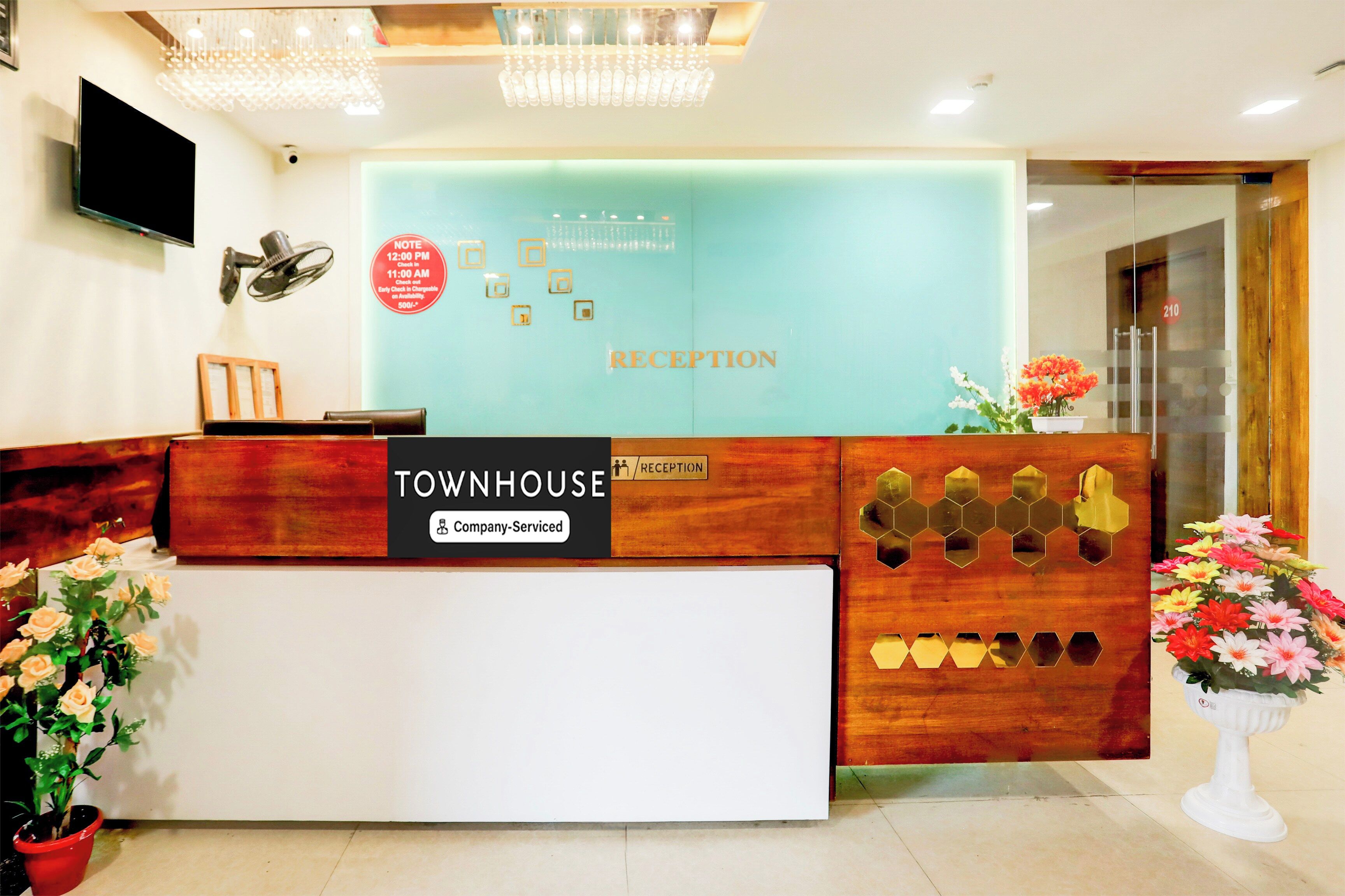 Una mesa de recepción con un letrero que dice 'Townhouse', una etiqueta que indica 'Recepción' y un aviso de 'Servicio de empresa'.