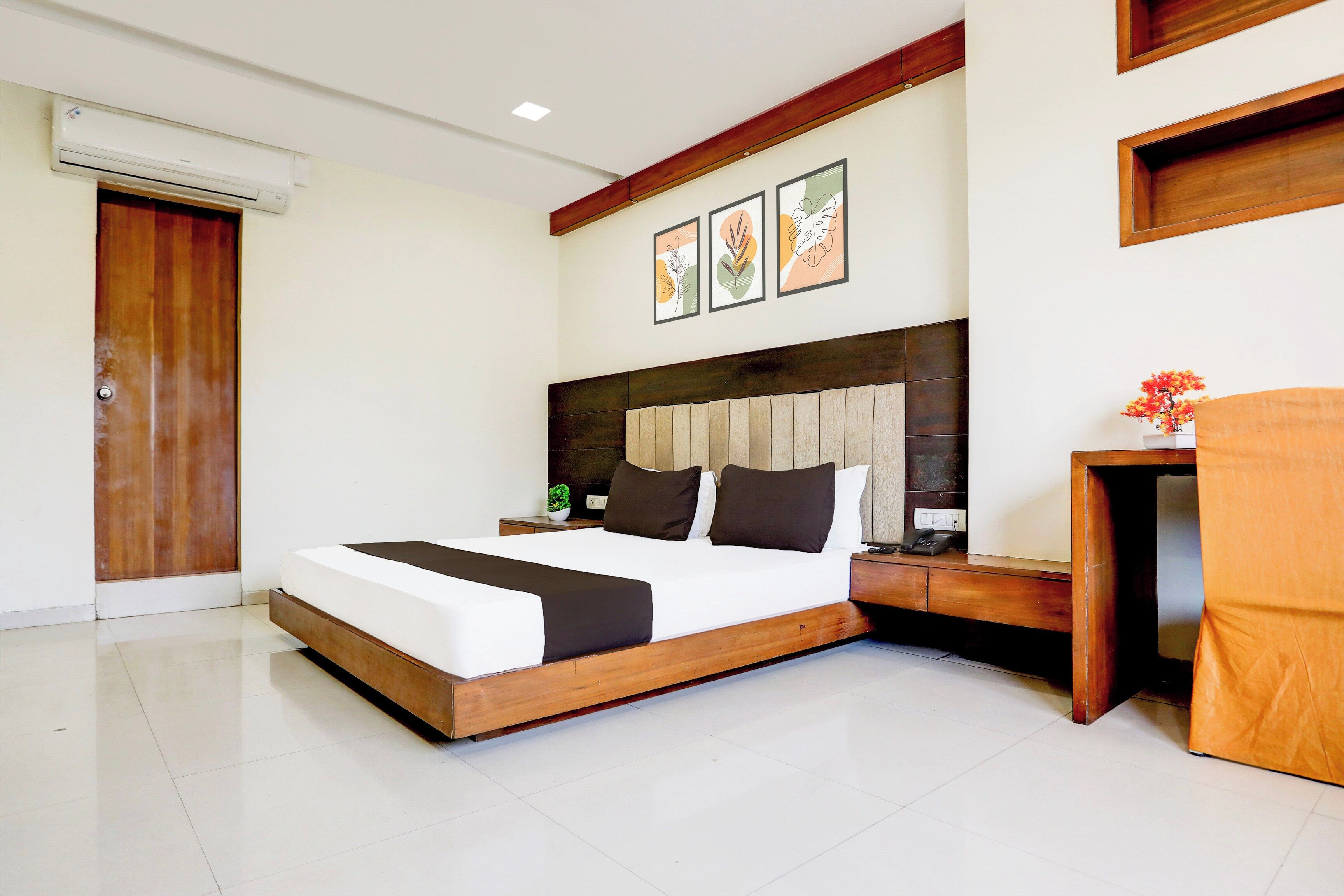 Habitación de hotel moderna con una cama grande, una mesita de noche, un escritorio y un aire acondicionado instalado en la pared.