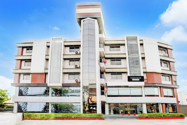Un edificio de varios pisos con una torre central, ventanas amplias y un letrero que indica que es una casa townhouse con servicios de empresa.