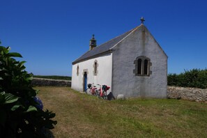A small church with a bell tower, a stone wall, and bicycles parked in front. - Panoramic Sea-view Apartment in Le Conquet (Le Conquet)
