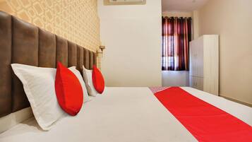 Habitación de hotel con cama, cabecero, armario y equipo de aire acondicionado.