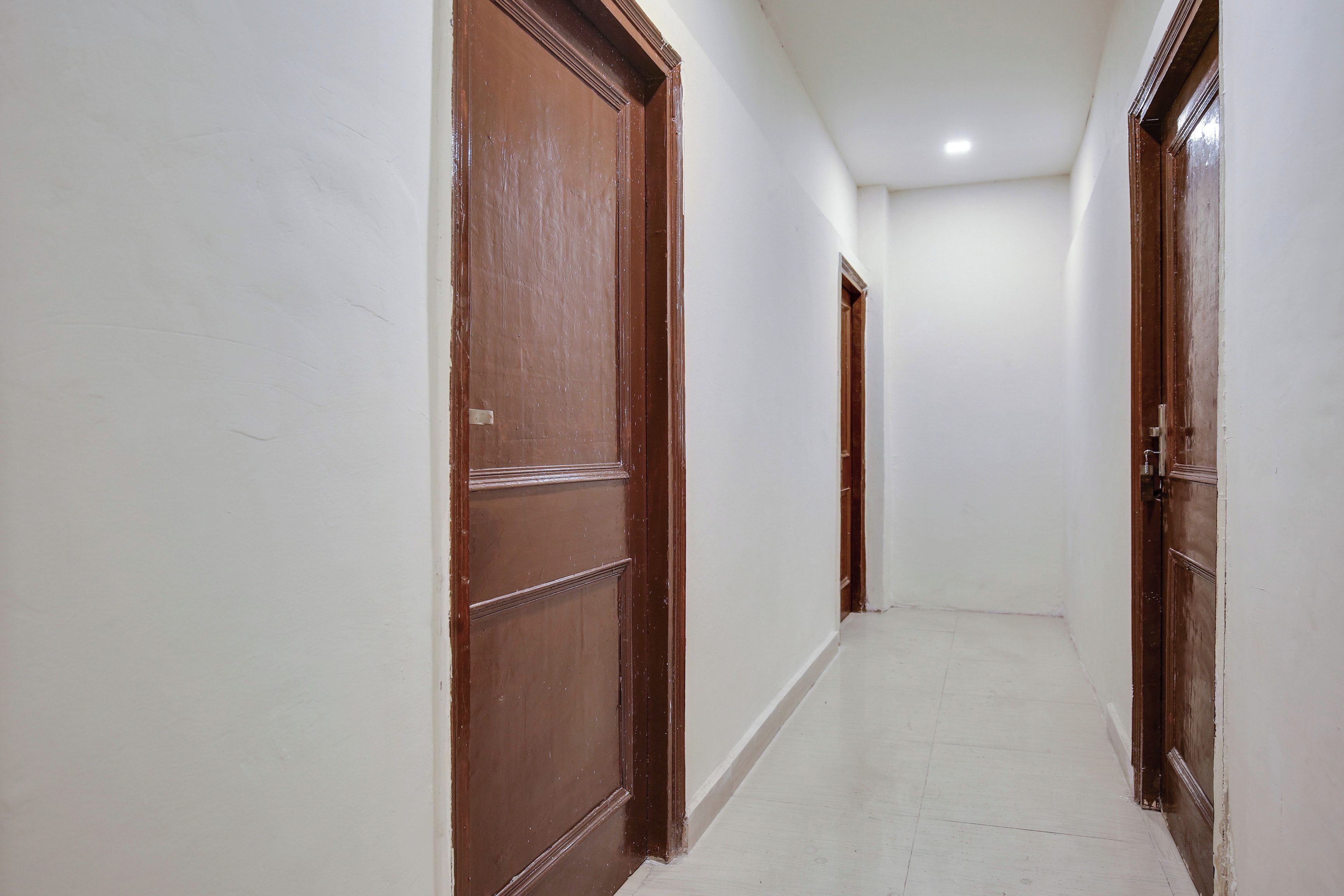 A corridor with wooden doors and white walls.