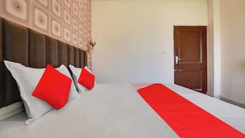 Habitación de hotel con una cama grande, cabecera con un diseño geométrico, una manta roja y una puerta.