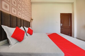 Habitación de hotel con una cama grande, cabecera con un diseño geométrico, una manta roja y una puerta.