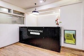 Uma receção com uma placa a indicar 'TOWNHOUSE Company Serviced' num interior moderno com soalho de madeira e um quadro emoldurado na parede.
