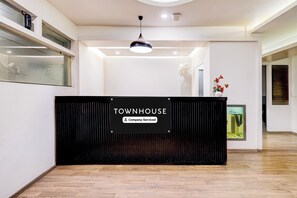 Un mostrador de recepción con un letrero que dice 'TOWNHOUSE Company-Serviced' en un interior moderno con piso de madera y una lámpara de techo.