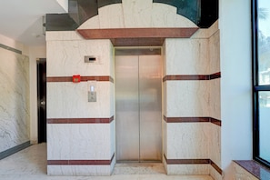 A modern elevator with marble walls and a red safety light. - Townhouse Civil Aviation HAL Road (Bangalore)