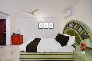 A hotel room with a bed, a nightstand, a ceiling fan, and wall art. - Townhouse Civil Aviation HAL Road (Bangalore)