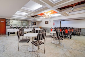 A restaurant with round tables and striped chairs, a chandelier, and a ceiling with skylights. - Townhouse Civil Aviation HAL Road (Bangalore)
