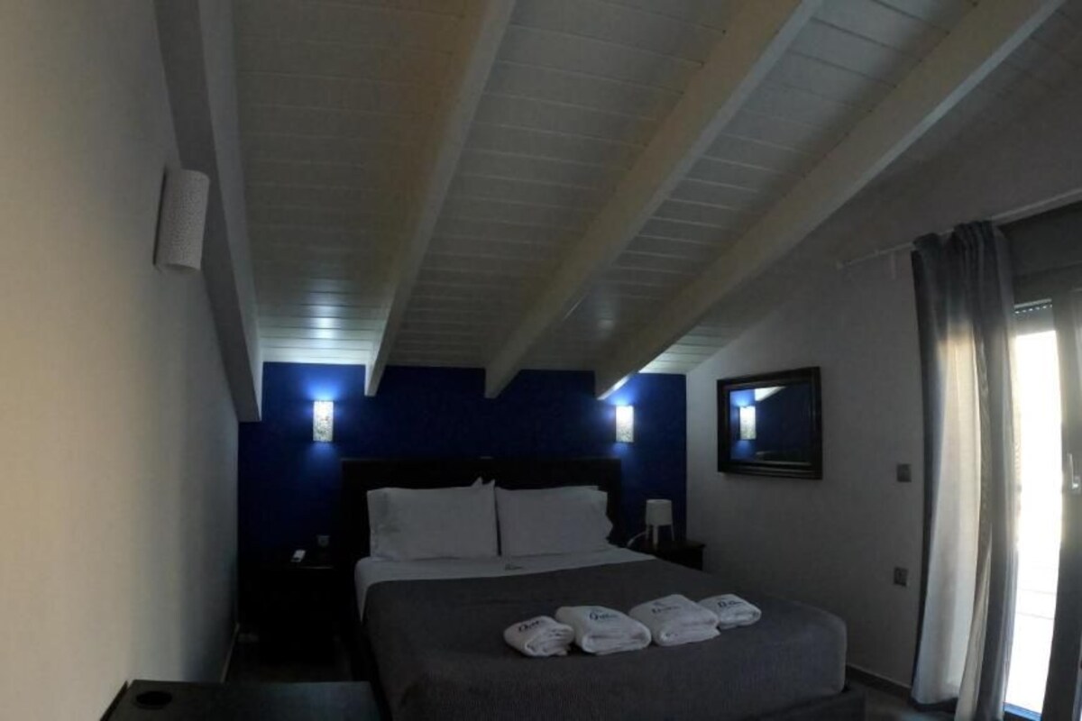 A hotel room with a bed, nightstands, a TV, and a window with curtains.