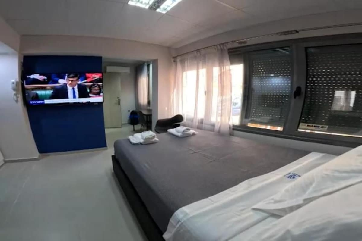 A hotel room with a bed, a television, a desk, and a window with curtains.