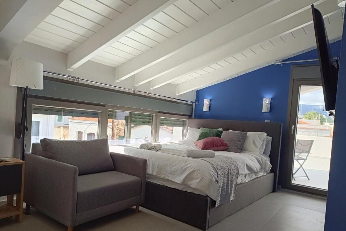 A bedroom with a bed, a sofa, a TV, and a window.